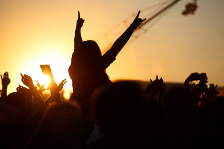 The crowd enjoys the summer music festival, sunset, the silhouettes hands up, Silhouette People Party Sunset Celebrate Dancing Conceptの写真素材