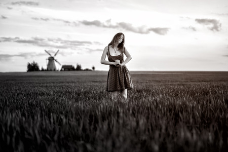 The girl in the green field. Summer. Mill on hamlet in the background. Monochromeの写真素材