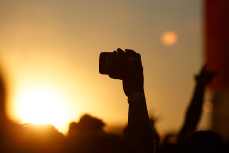 Silhouette of smartphone in a hand over crowd