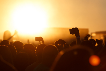 Silhouette of smartphone in a hand over crowdの写真素材