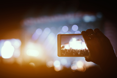 Hand with a smartphone records live music festival and taking photo of concert stageの写真素材