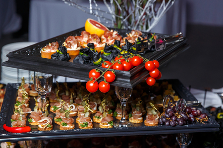Cherry tomatoes on catering banquet table with canape, vegetables and fruits. Variety of tasty delicious snacks on the tableの写真素材