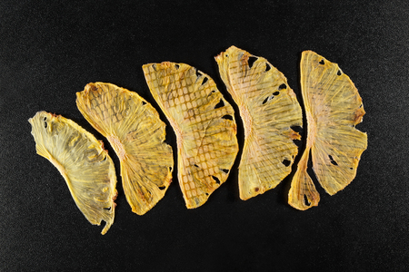 Five slices of dried pineapple on black background, top viewの写真素材