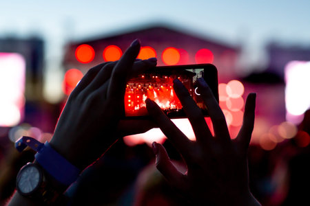 silhouette of hands with a smartphone at a big music festival, video recording