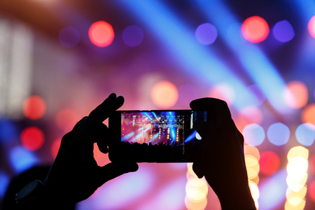 Silhouette of young man, taking photo rock concert on the mobile phone, outdoor festの写真素材