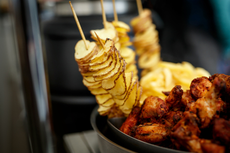 Homemade organic baked fried thin potatoes chips. Chicken wings on background. Snacks for beerの写真素材