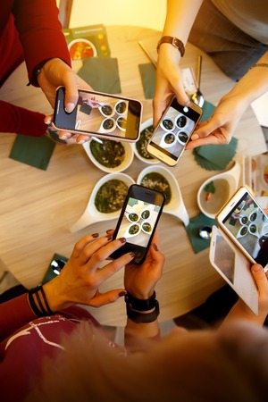 Close up hands of woman taking photo of dinner food on the table. A lot of smartphonesの写真素材