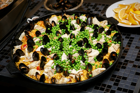 Spanish seafood paella with mussels, mollusks, peas in traditional pan.の写真素材