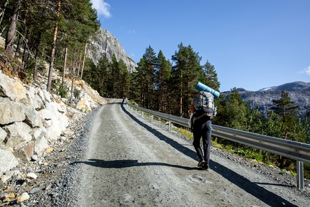 tourist with a backpack is walking along a gravel roadの写真素材