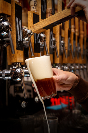 Barman hands pouring a dark beer in a glass.の写真素材