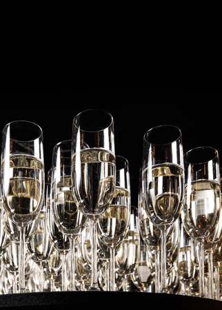 A row of glasses filled with champagne are lined up ready to be served.の写真素材