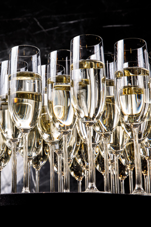 A row of glasses filled with champagne are lined up ready to be served.の写真素材