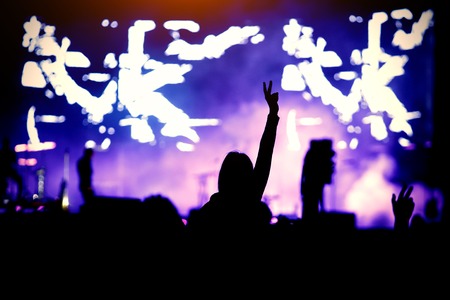 Silhouette of a girl at a concert, the pleasure of the show. Raised handsの写真素材