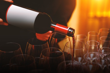 Waiter pouring red wine into glasses at eventの写真素材
