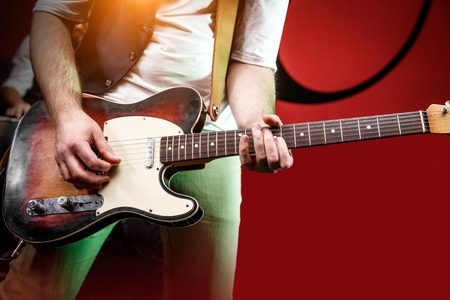 Guitarist hand play guitar on concert stage with red light, Practicing music instrument.の写真素材