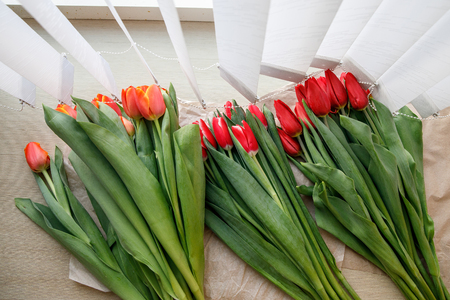 Colorful fresh tulip flowers on the windowsill near the blinds. Flowers for mother's day or women's dayの写真素材