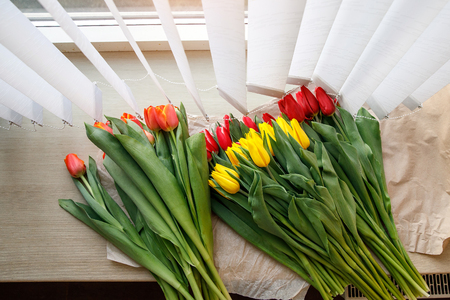 Colorful fresh tulip flowers on the windowsill near the blinds. Flowers for mother's day or women's dayの写真素材