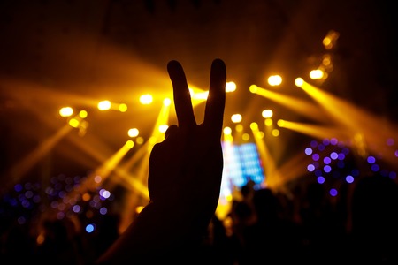 Black silhouette of the hand against the background of the concert scene. Two fingersの写真素材