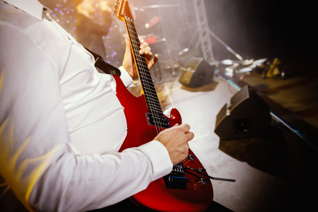 Guitarist hand play guitar on concert stage with red guitar, Practicing music instrument.の写真素材