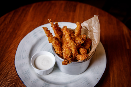 Golden crisp fried crumbed chicken nuggets served in a metal dish as an appetizer or finger food on dark bar backgroundの写真素材