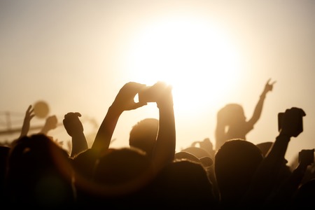 A lot of hands on the summer music festival. Using a smartphone. Silhouettesの写真素材