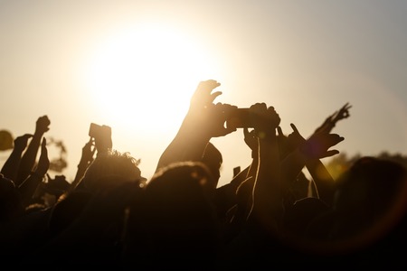 A lot of hands on the summer music festival. Using a smartphone. Silhouettesの写真素材