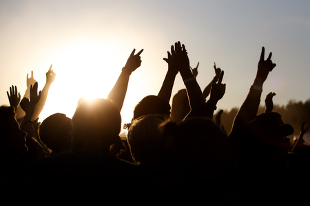 People celebrating on an summer open air. Shillouettes of raised handsの写真素材