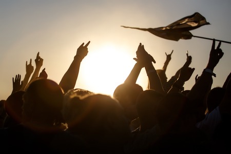 People celebrating on an summer open air. Shillouettes of raised handsの写真素材