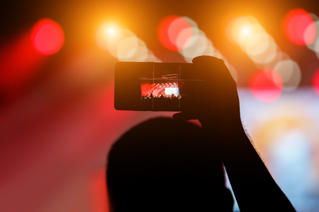 Record on a mobile phone of a concert, show. Holds a smartphone in handの写真素材