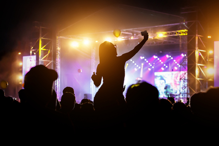 Silhouette of the girl with smartphone gets pleasure from the rock concertの写真素材