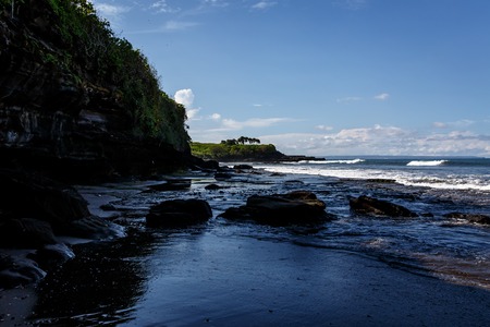Volcanic coast with rocks and black sand on Bali island, Indonesiaの写真素材