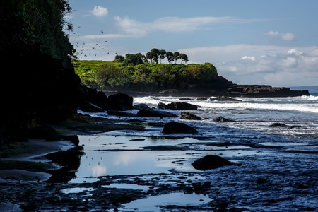 Volcanic coast with rocks and black sand on Bali island, Indonesiaの写真素材