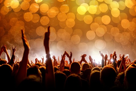Crowd with raised hands at a concert, light show, bubbles bokehの写真素材