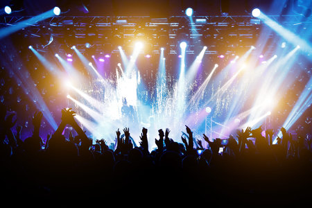 Satisfied people at the concert, colored light from the stage