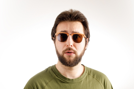 Advertising portrait of a man. Sunglasses and a green T-shirt. Emotion of wonder, surpriseの写真素材