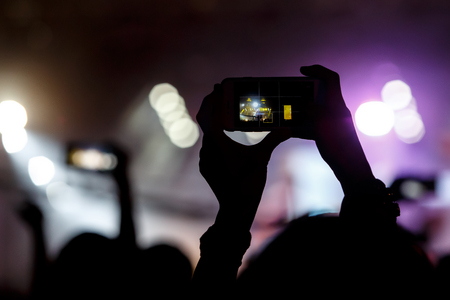 Shoots a   video on a mobile phone at a concert.の写真素材