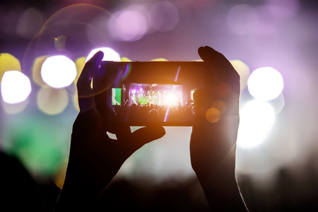 Shoots a video on a mobile phone at a concert.の写真素材
