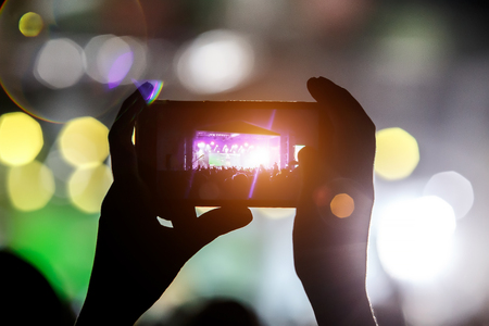 Shoots a video on a mobile phone at a concert.の写真素材