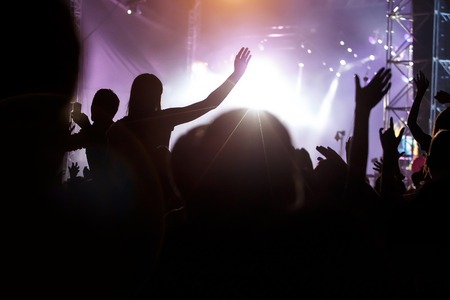 Fans with hands up against a music festival sceneの写真素材