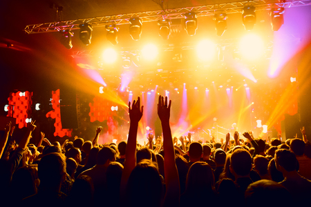 People with their hands up at a concert of their favorite group. Crowd watching a showの写真素材