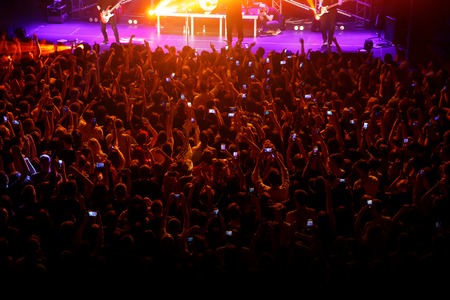 People with their hands up and smartphones at a concert of their favorite group. Crowd watching a showの写真素材