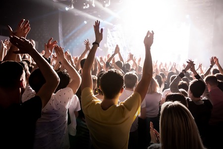 Raised hands in honor of a musical show on stage, People in the hallの写真素材