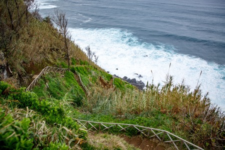 Walking trail along the sea, ladder with railing on the background of wavesの写真素材