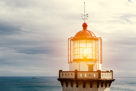 Head of old vintage lighthouse with turned on lampの写真素材