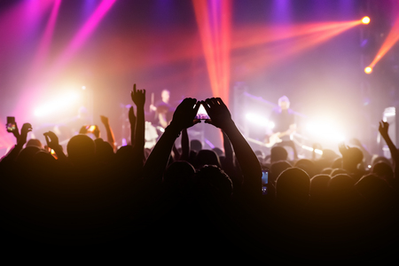 Crowd with raised hands and smartphone record a concertの写真素材