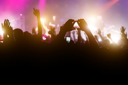 Crowd with raised hands and smartphone record a concertの写真素材