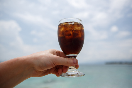 Cooling drink in hand on beach.の写真素材