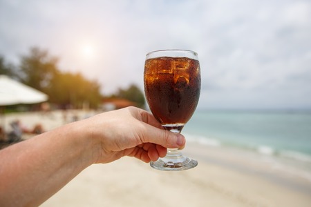Cooling drink in hand on beach.の写真素材