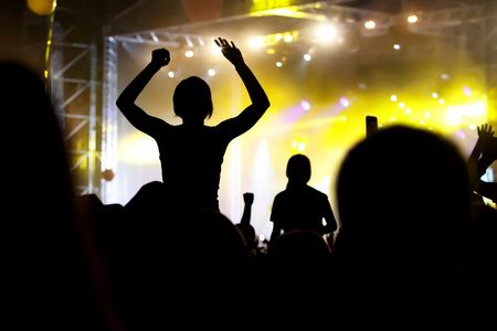 People silhouettes with raised hands at outdoor music showの写真素材