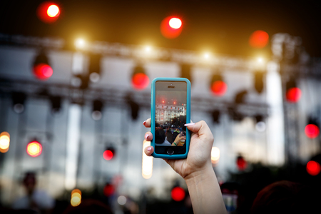 Using a mobile phone at a summer music showの写真素材